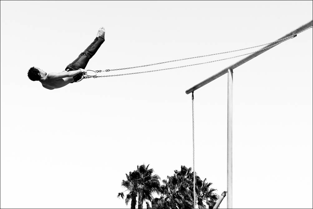 Energize. A photograph of a gymnast suspended on the swinging rings in Santa Monica, CA USA. Photograph by Jeff Kauffman.