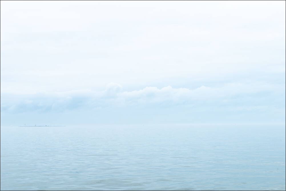 See The Sea. Through The Mist. A photograph by Jeff Kauffman showing soft fog and mist on steely gray waters. A small island can be seen on the horizon through the mist. Galveston, Texas USA. ©Jeff Kauffman